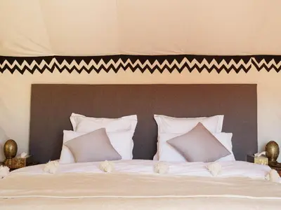 a large bed with white sheets and pillows at Nubia Luxury Camp Erg Chegaga in El Gouera