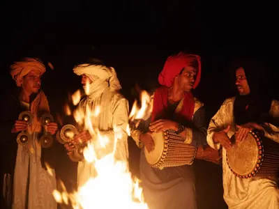 a group of women standing in front of a fire at Nubia Luxury Camp Erg Chegaga in El Gouera