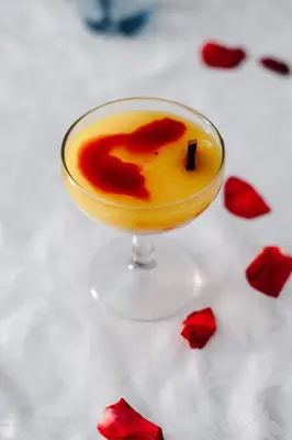 a drink in a glass on a table with red flowers at Kasbah Rayane Ait Ben Haddou in Aït Ben Haddou
