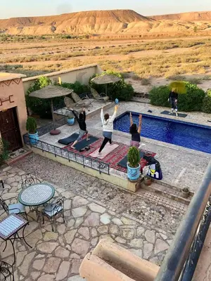 a group of people doing a yoga pose by a pool at Kasbah Rayane Ait Ben Haddou in Aït Ben Haddou