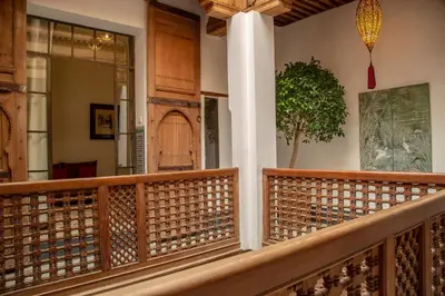 a balcony with a wooden railing and a tree on the wall at La Maison Maure in Fès