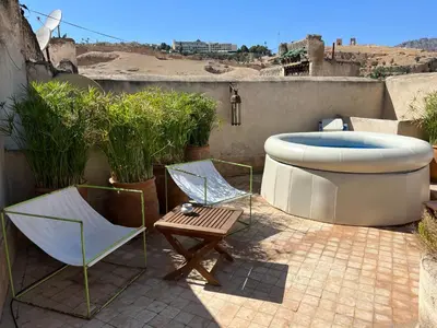 a patio with a tub and two chairs and a table at La Maison Maure in Fès