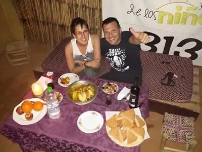 a man and woman sitting at a table with food at Obira Oasis Merzouga Camp in Merzouga