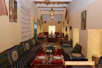 a living room with couches and tables in a room at Palmeraie Guest House in Tinerhir