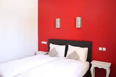 two beds in a room with a red wall at Auberge Tinit in Er Rachidia