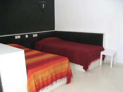 a room with two beds and a table in it at Auberge Tinit in Er Rachidia
