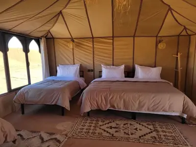 a bedroom with two beds in a tent at Ammar Luxury Camp in Merzouga