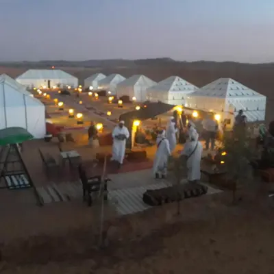 a group of people standing in front of tents in the desert at Ammar Luxury Camp in Merzouga