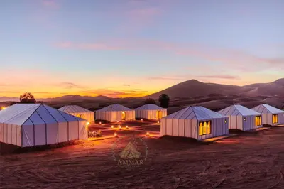 a group of tents in the desert at sunset at Ammar Luxury Camp in Merzouga