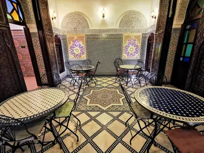 a room with tables and chairs and a tile floor at Riad Farah in Fès
