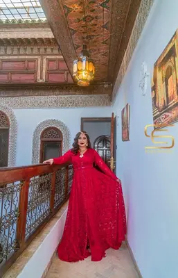 a woman in a red dress standing on a balcony at Riad Farah in Fès