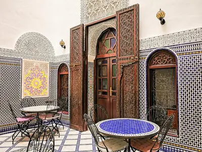 a patio with tables and chairs in a building at Riad Farah in Fès