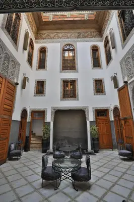 a room with a table and chairs in a building at Riad Layla in Fès