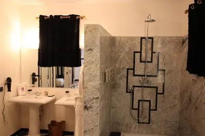 a bathroom with a sink and a shower and a mirror at O'Atlas in El Harkat