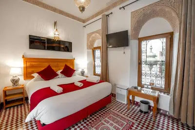 a bedroom with a large bed with red and white sheets at Dar D'or Fes in Fès