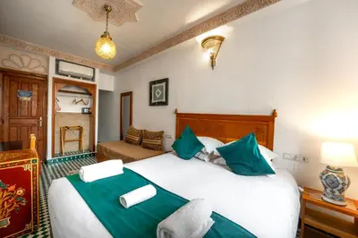 a bedroom with a large white bed with green pillows at Dar D'or Fes in Fès