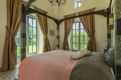 a bedroom with a large bed in a room with windows at Villa Akhdar 18 in Ben Larbi