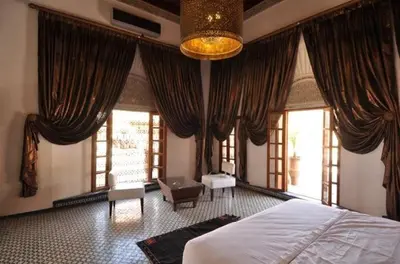 a bedroom with curtains and a bed and a chair at Riad Said in Fès