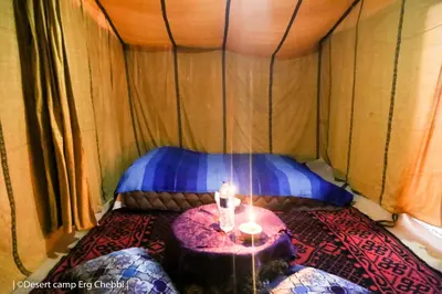 a small room with a bed in a tent at Desert Camp Erg Chebbi in Merzouga