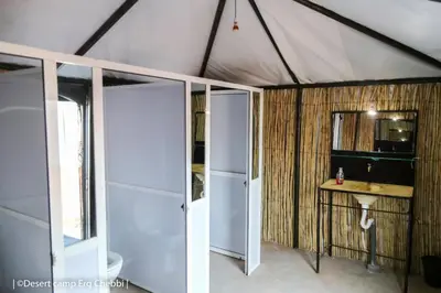 a room with a toilet and a sink in a tent at Desert Camp Erg Chebbi in Merzouga