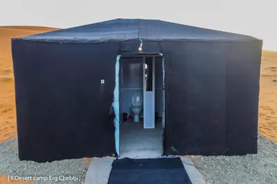 a black building with a toilet in it at Desert Camp Erg Chebbi in Merzouga