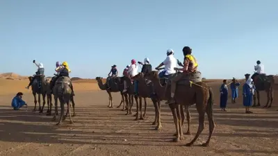 a group of people riding horses in the desert at Desert Camp Erg Chebbi in Merzouga