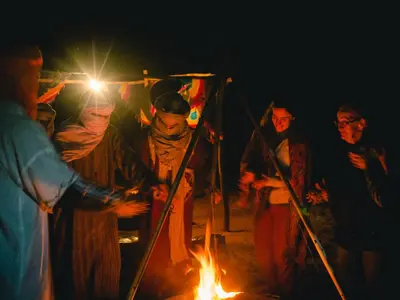 a group of people standing around a fire at Desert Camp Erg Chebbi in Merzouga