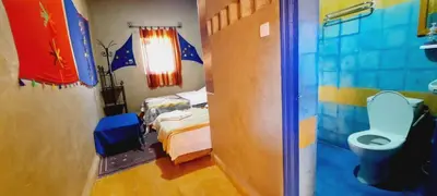 a bathroom with a bed and a toilet in a room at Hôtel Riad Tadarte Familier in Merzouga