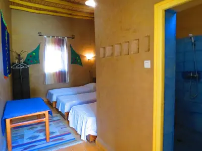 a room with three beds and a shower at Hôtel Riad Tadarte Familier in Merzouga