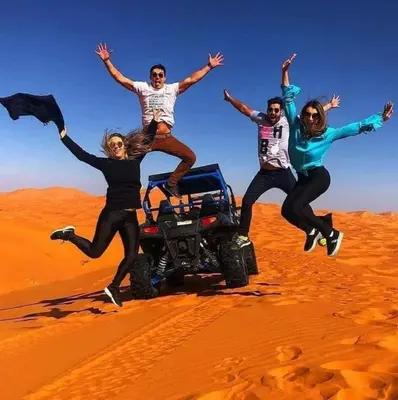 a group of people jumping in the desert at Hôtel Riad Tadarte Familier in Merzouga