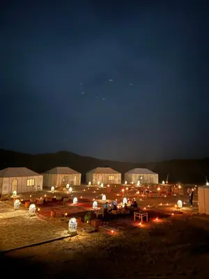 a group of tents in a field at night at Desert Luxury Camp Merzouga in Merzouga