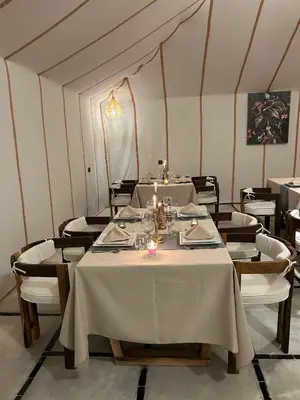 a dining room with white tables and chairs with candles at Desert Luxury Camp Merzouga in Merzouga