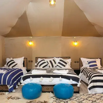 two beds in a room with blue and white stripes at Desert Luxury Camp Merzouga in Merzouga