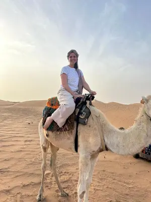 a woman riding on a camel in the desert at Desert Luxury Camp Merzouga in Merzouga