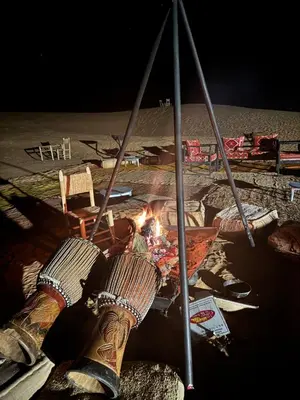 a fire in the middle of a beach with boots at Desert Luxury Camp Merzouga in Merzouga