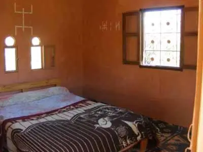 a small bedroom with a bed with a cross on it at kasbah Ait arbi in Aït Ougliff
