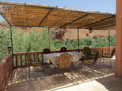 a patio with a table and chairs under a pergola at kasbah Ait arbi in Aït Ougliff