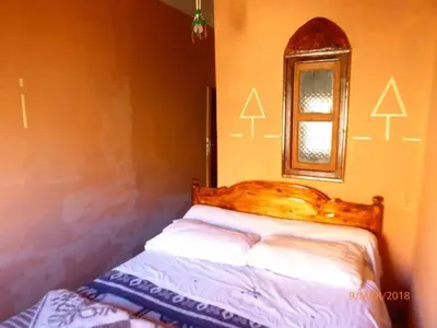 a bedroom with a bed and a mirror and a window at kasbah Ait arbi in Aït Ougliff
