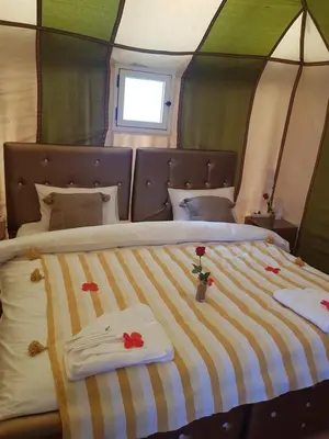 a bed in a tent with towels and flowers on it at MorokoTour Camp in Merzouga
