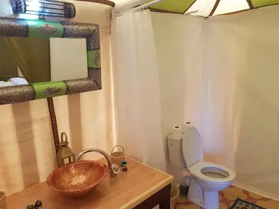 a bathroom with a sink and a toilet and a mirror at MorokoTour Camp in Merzouga