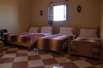 two beds in a room with a checkered floor at Auberge La Source in Merzouga