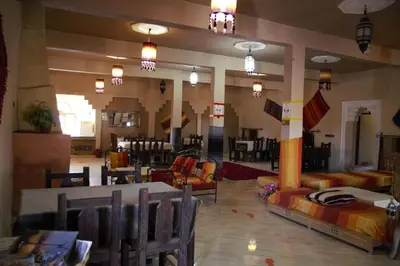a large room with tables and chairs and a dining room at Auberge La Source in Merzouga