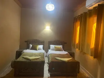 a bedroom with two beds and a light on the wall at Sunny Place apartments in Merzouga