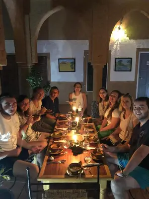 a group of people sitting around a wooden table at Riad Nkob in Nkob