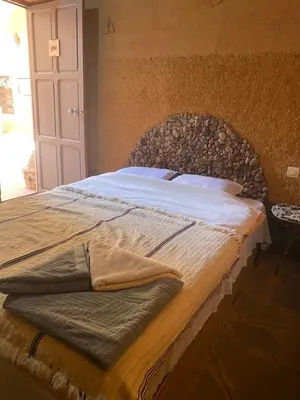 a bedroom with a large bed with a wooden headboard at Riad Nkob in Nkob