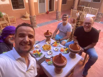 a group of men sitting around a table with food at Riad Nkob in Nkob
