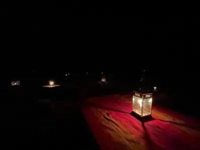 a lantern in the dark with lights in the background at Mhamid Sahara Camp Activities - Le Chant du Sable in Mhamid