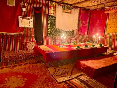 a room with a table and two beds in it at Mhamid Sahara Camp Activities - Le Chant du Sable in Mhamid
