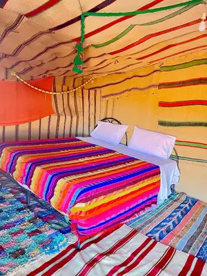 a colorful striped bed in a room at Mhamid Sahara Camp Activities - Le Chant du Sable in Mhamid