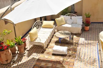 a balcony with chairs and a table and an umbrella at La Cheminée Bleue Fes in Fès